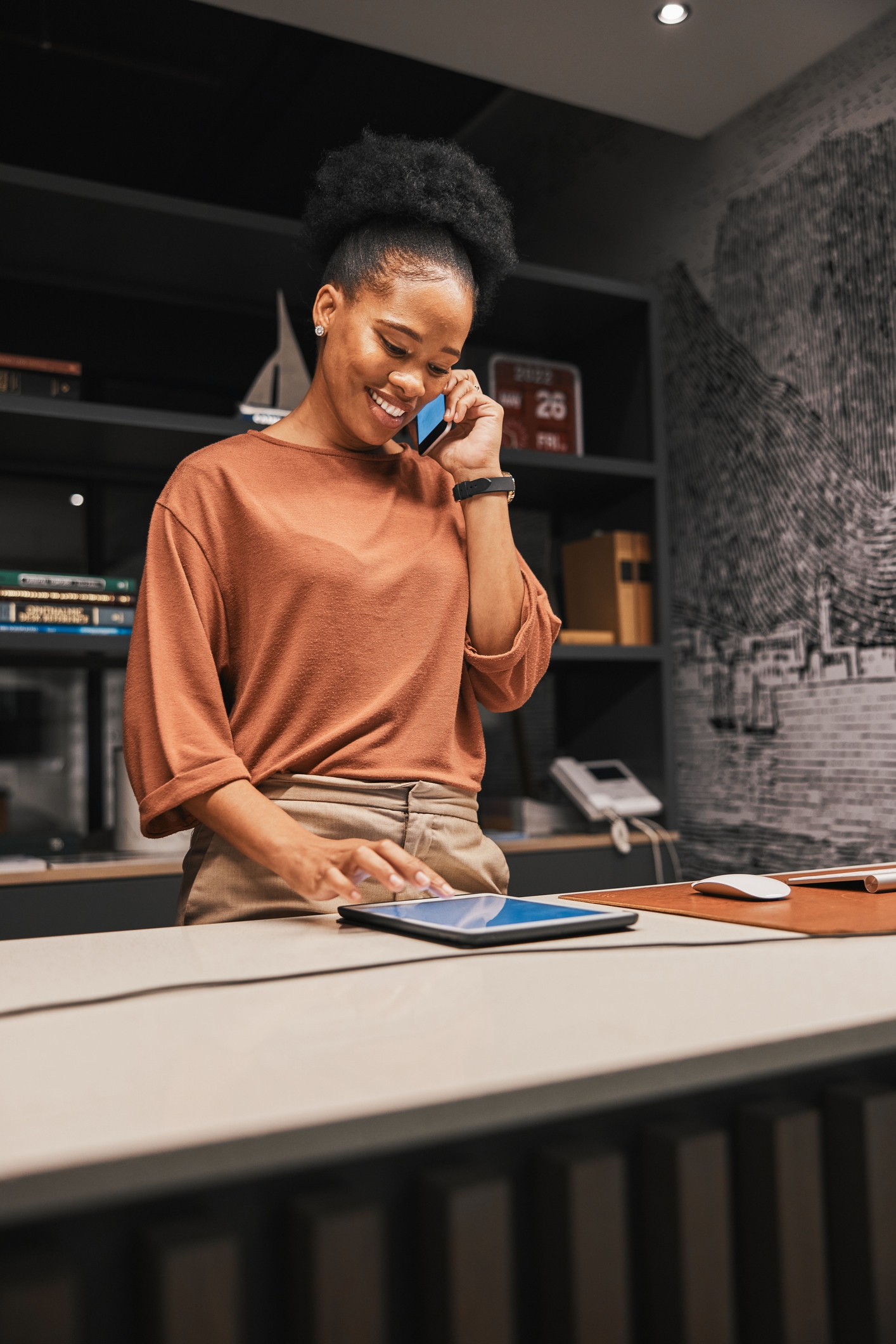 Woman standing behind counter while speaking on the telephone