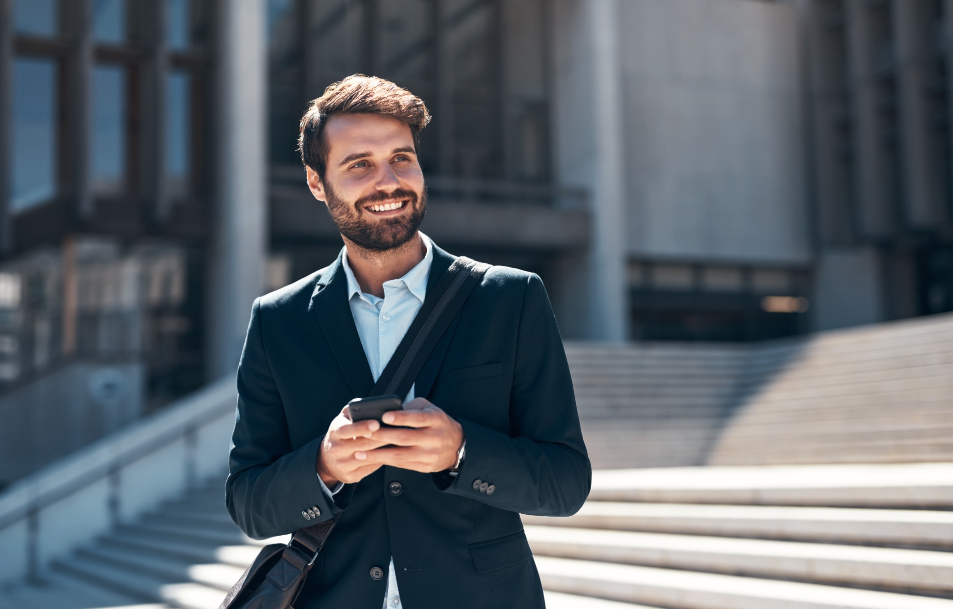 Man holding phone on steps leading to an office building
